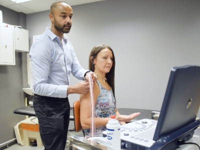 Dr Ronnie using the ultrasound on a shoulder.