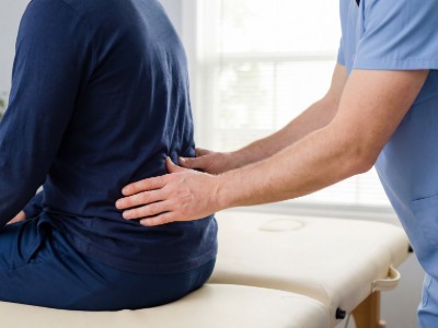 Chiropractor treating a patient's lower back pain with manual therap